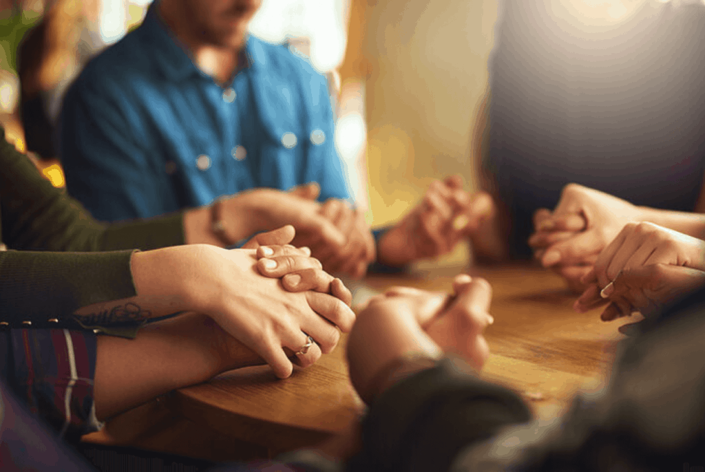 people sitting around a table holding hands