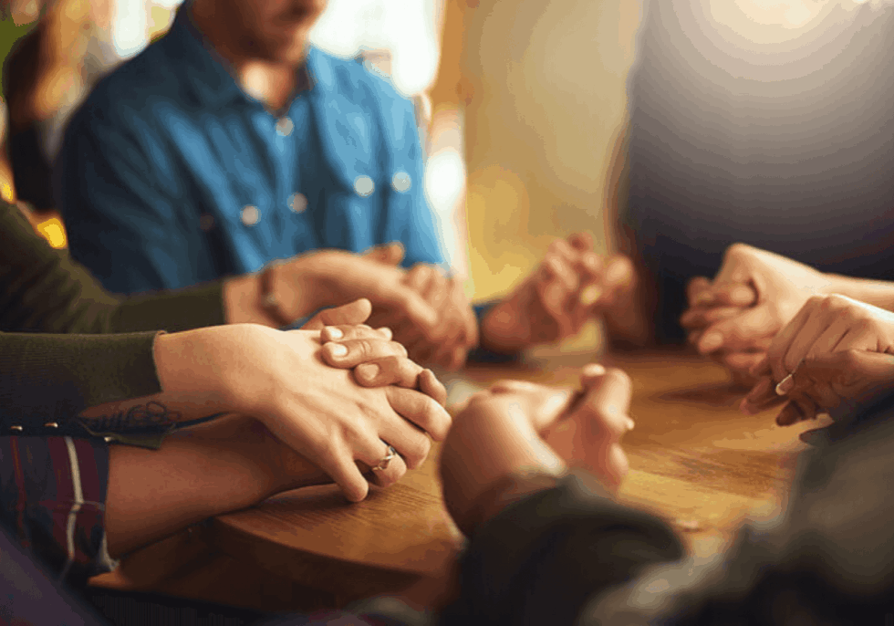 strategic-doing-faith-communities people sitting around a table holding hands